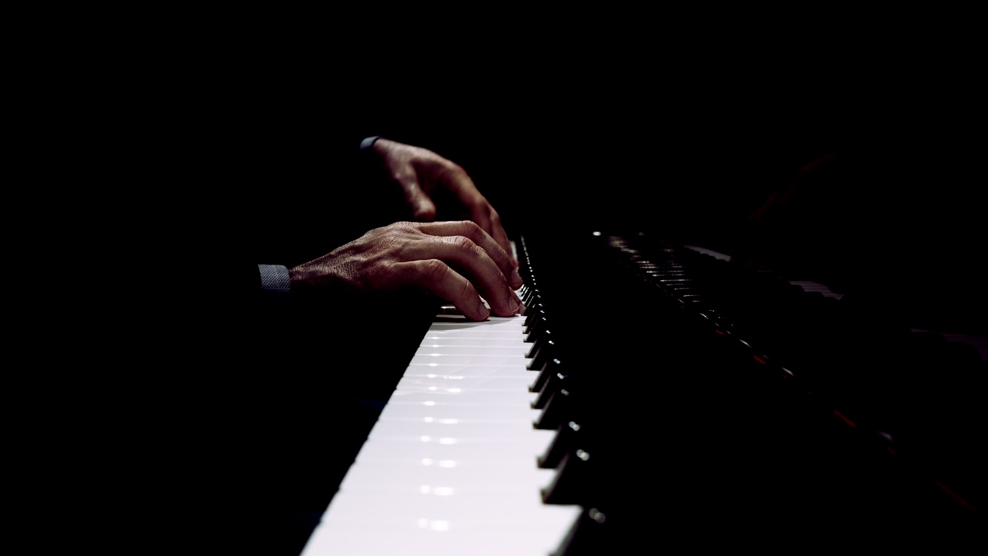 Hands at the piano in low light